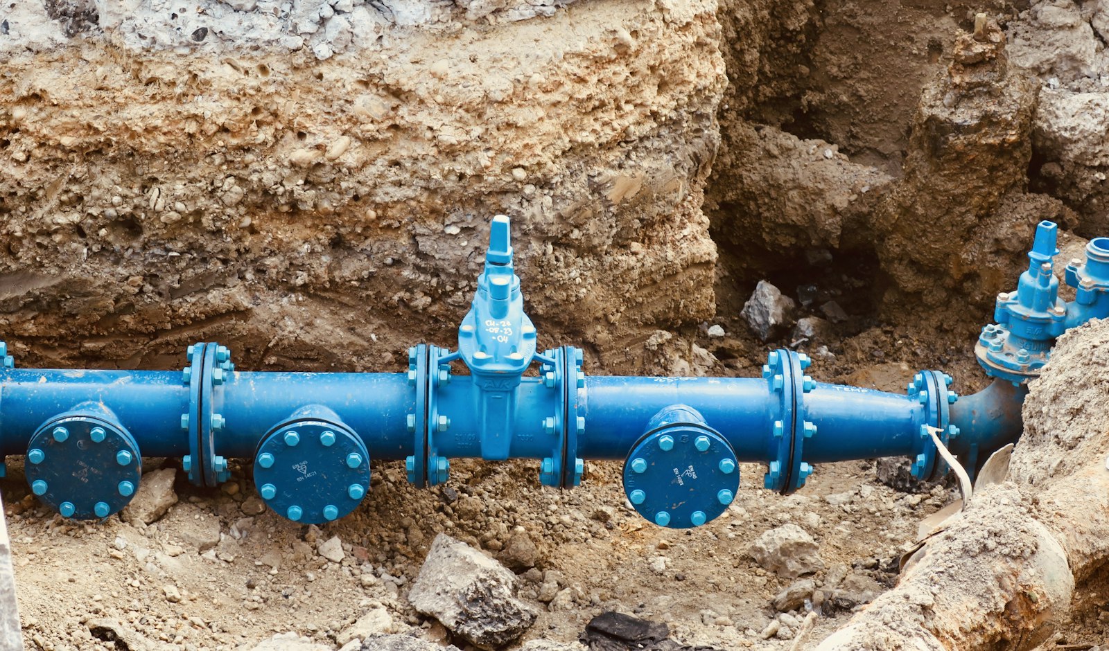 Blue water main pipes and valves in an open trench